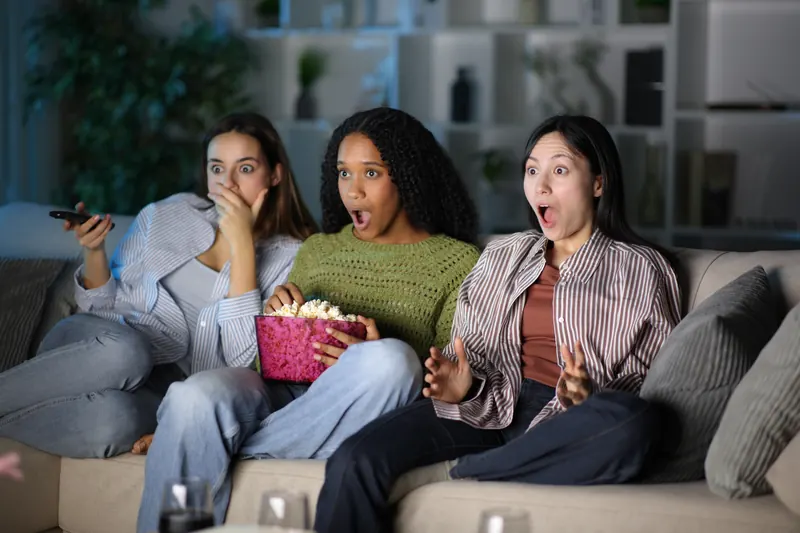 Friends reacting to the television from a sofa