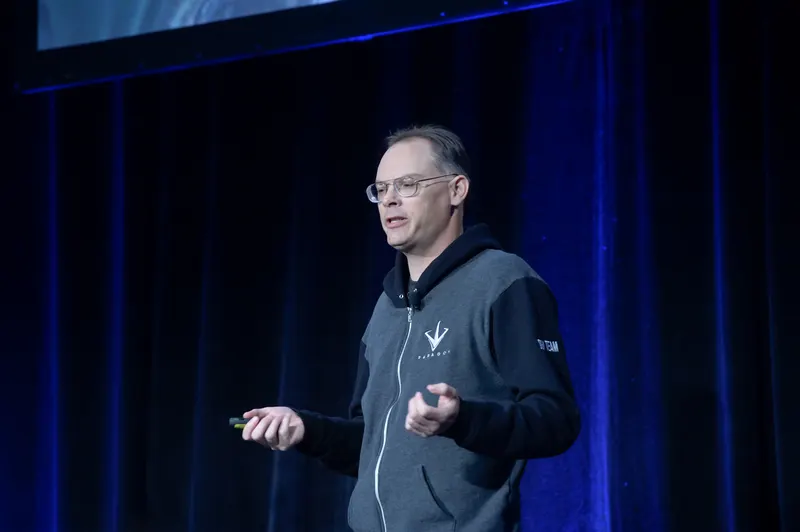 Tim Sweeney speaking on stage in a dark hoodie