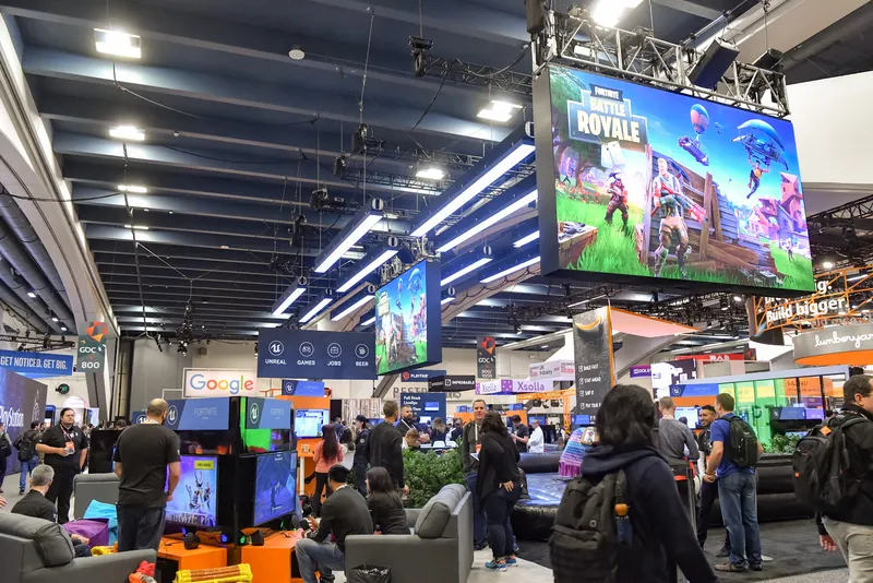 Large Fortnite Battle Royale screens above a busy expo floor