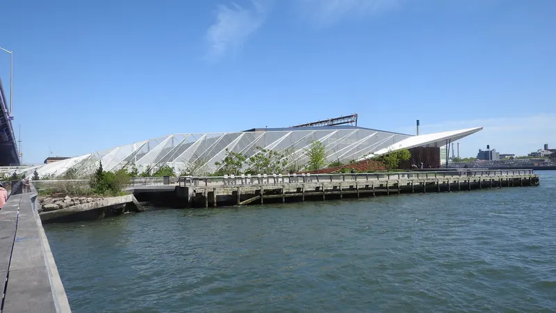 Pier 36 building with its white angled roof beside the East River