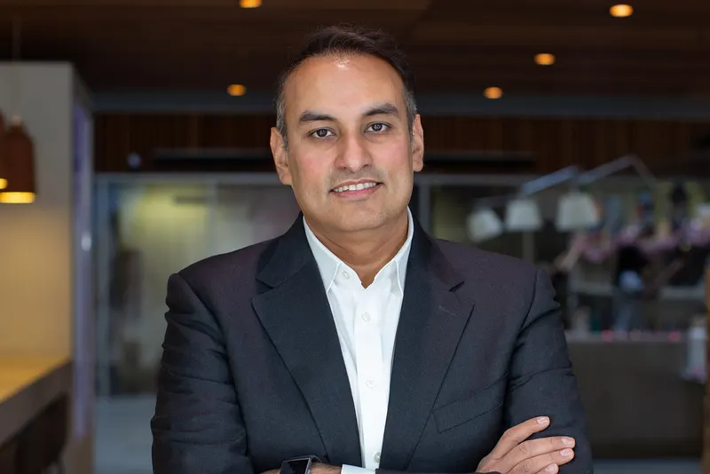 Namit Malhotra in a dark blazer and white shirt with arms folded