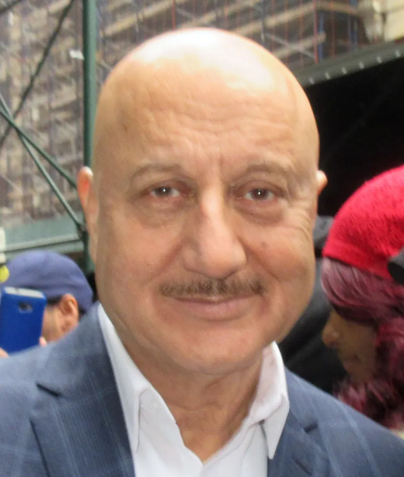 Anupam Kher smiling outdoors in a dark jacket