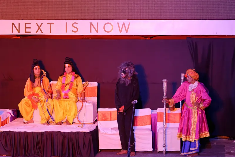 Costumed Ramlila performers on a stage lit in pink and purple