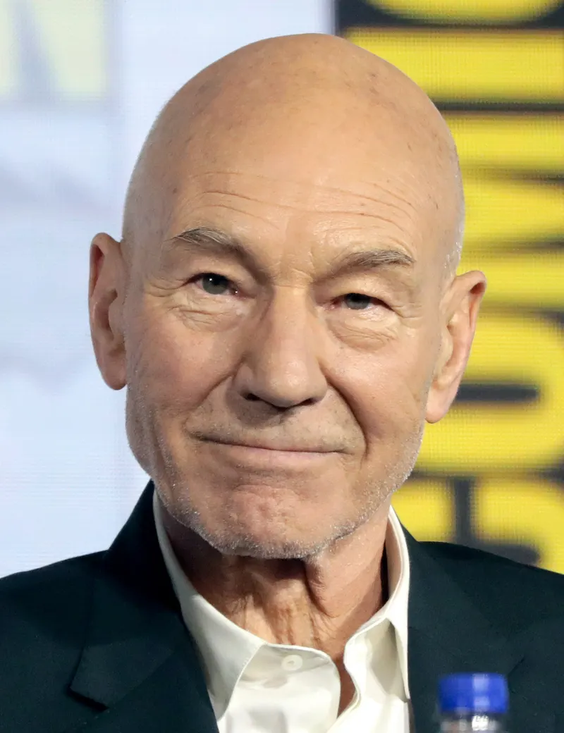 Close portrait of a smiling Patrick Stewart in a dark jacket and white shirt
