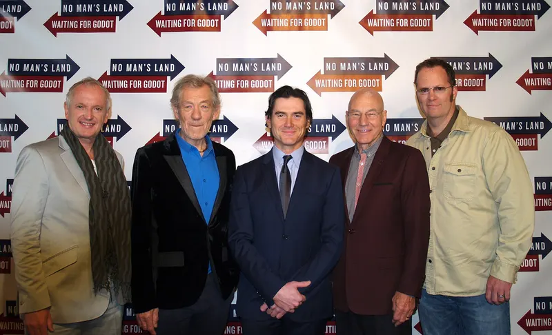 Five men posing in front of a Waiting for Godot and No Man's Land backdrop, Patrick Stewart second from right