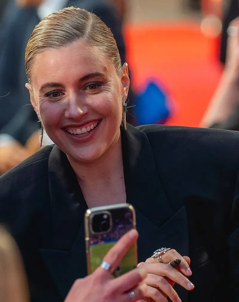 Greta Gerwig smiling at an outdoor event
