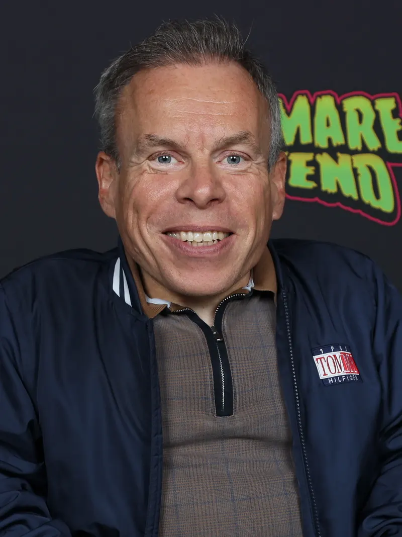 Warwick Davis smiling at a fan event