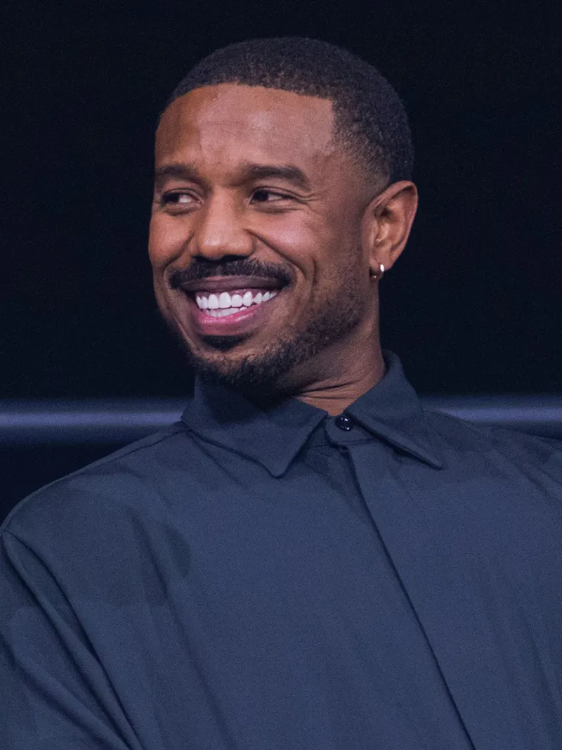 Michael B. Jordan smiling broadly in a dark shirt