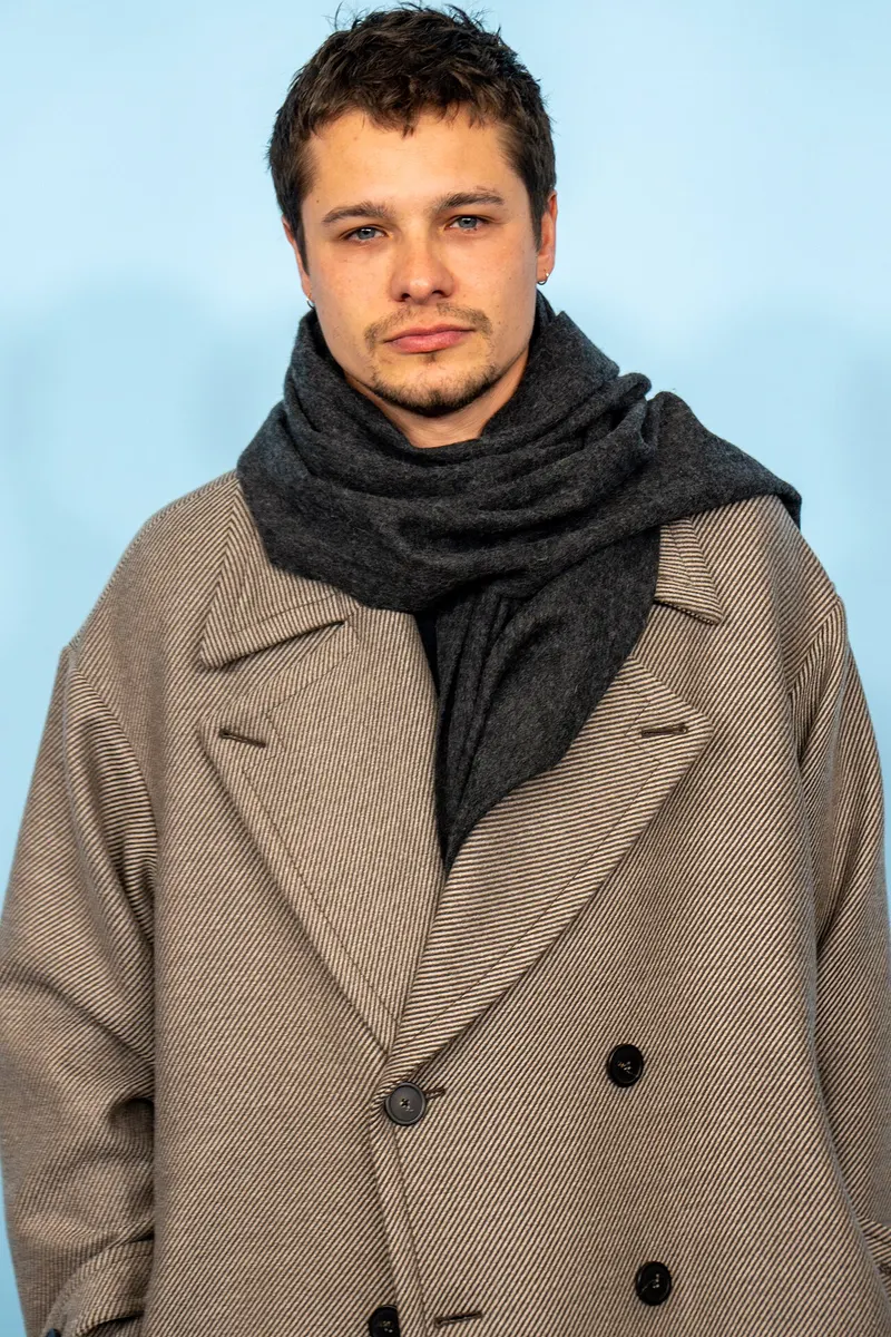 Toby Wallace in a grey coat and scarf