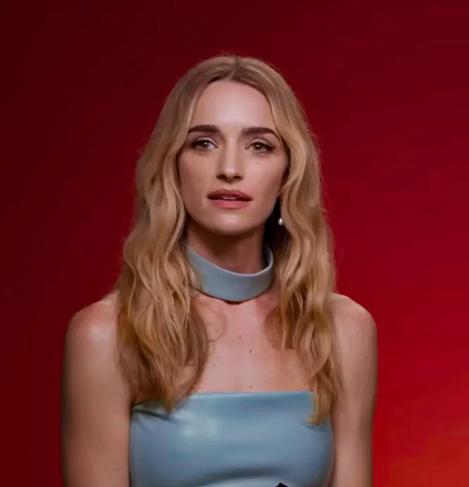 Brianne Howey with long wavy hair against a red background