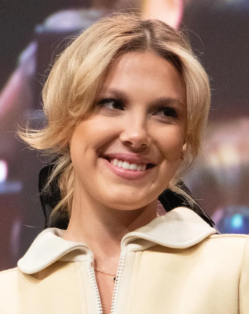Millie Bobby Brown smiling in a cream jacket