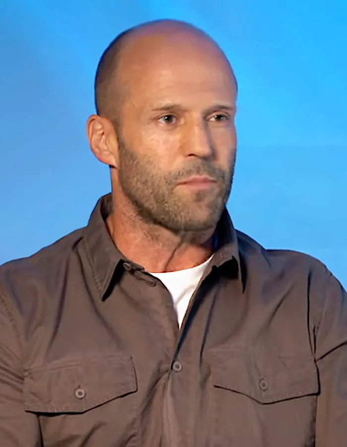 Jason Statham in a brown shirt against a blue background