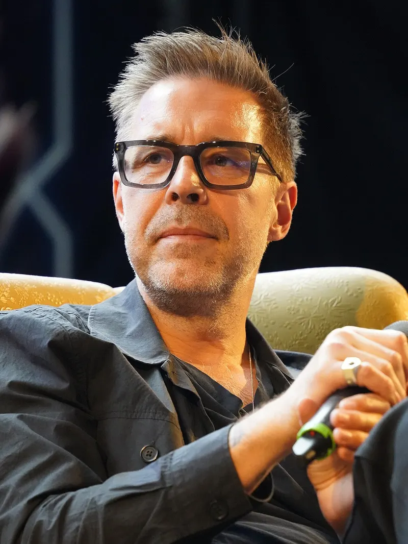 Paddy Considine in glasses holding a microphone
