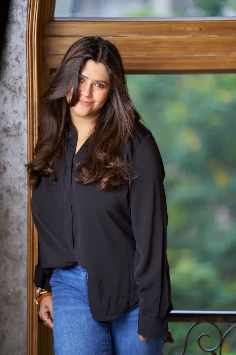 Ektaa Kapoor in a black shirt standing by a window