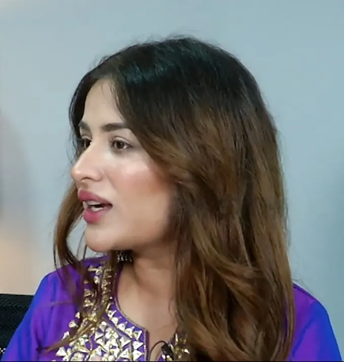 Sara Gurpal in a purple outfit speaking during an interview