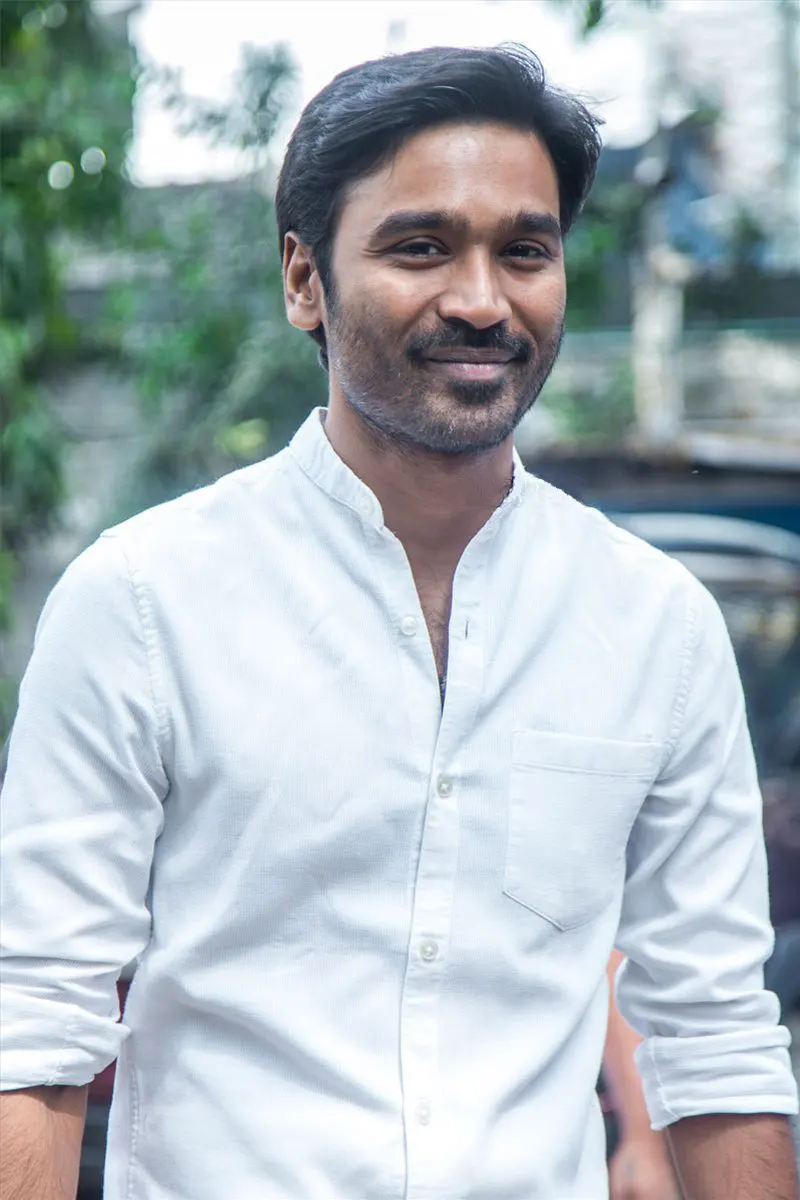 Dhanush smiling in a white shirt outdoors