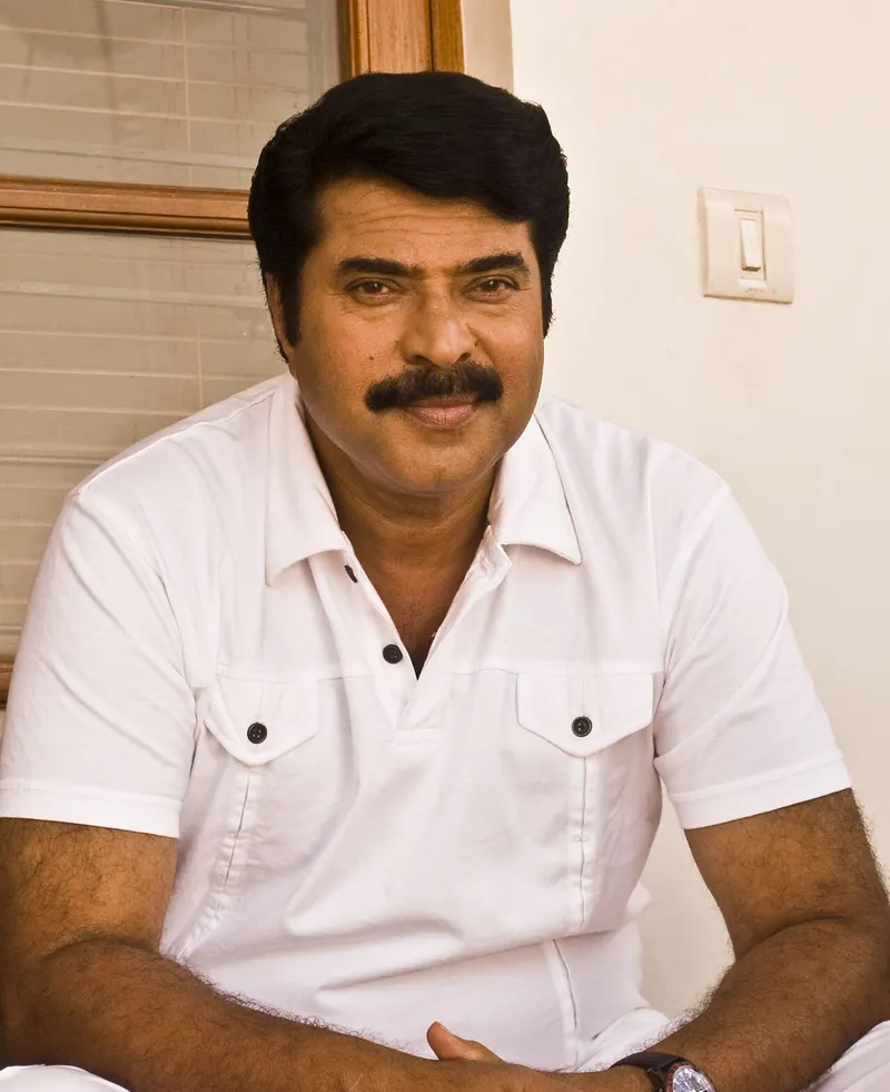 Mammootty seated in a white shirt, smiling