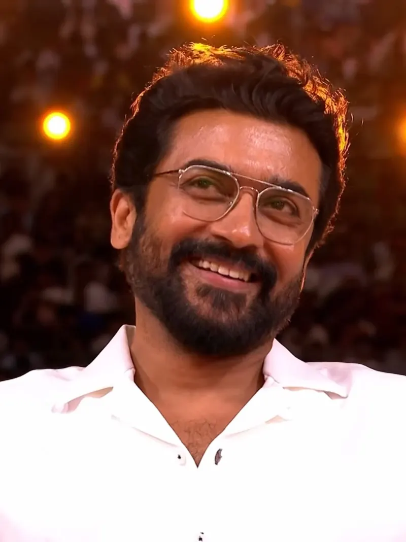 Suriya smiling in glasses on stage