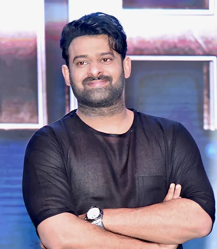 Prabhas smiling with arms folded at a film event