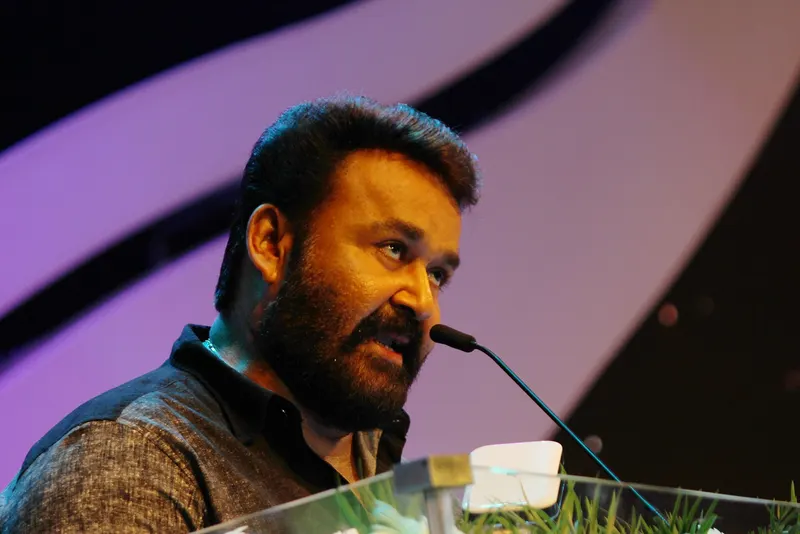 Mohanlal speaking at a microphone on stage