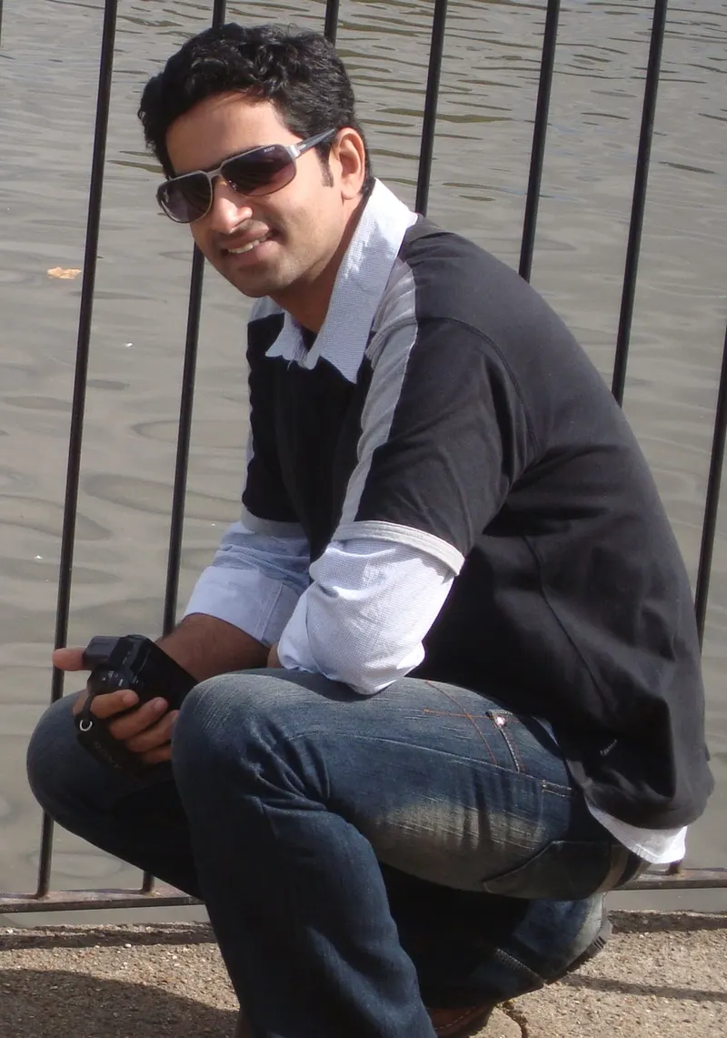 Saiju Kurup in sunglasses crouching by a river