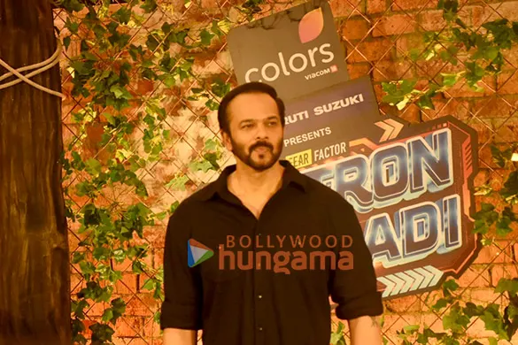 Rohit Shetty in a black shirt in front of a Khatron Ke Khiladi sign
