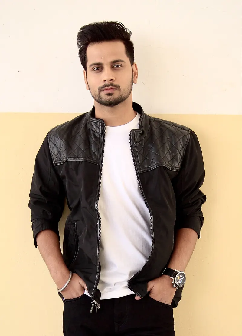 Raghveer Boli in a black jacket standing against a wall