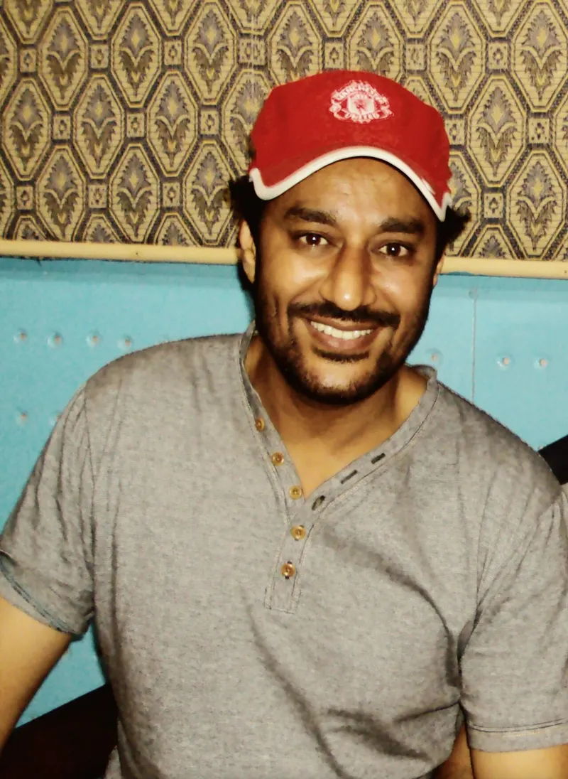 Harbhajan Mann smiling in a red cap