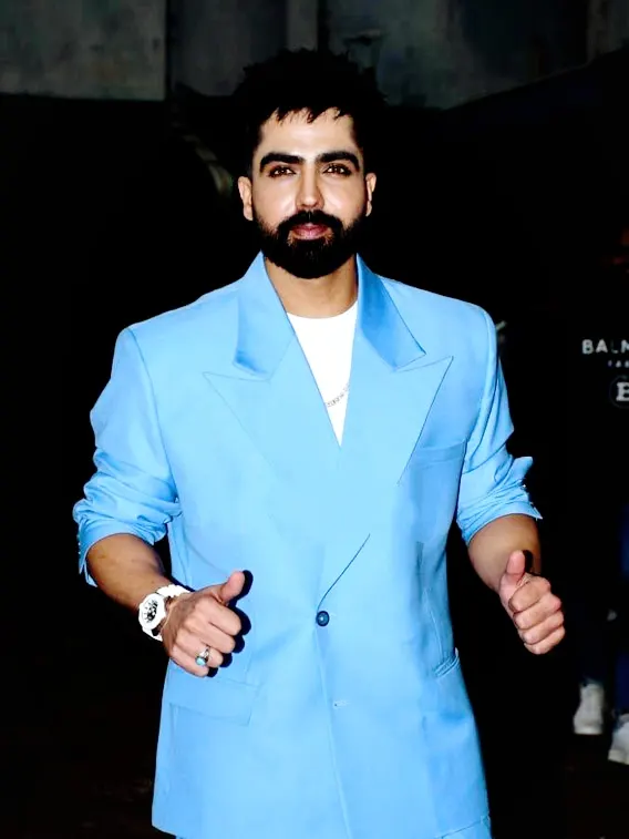 Harrdy Sandhu in a light blue suit giving a thumbs up