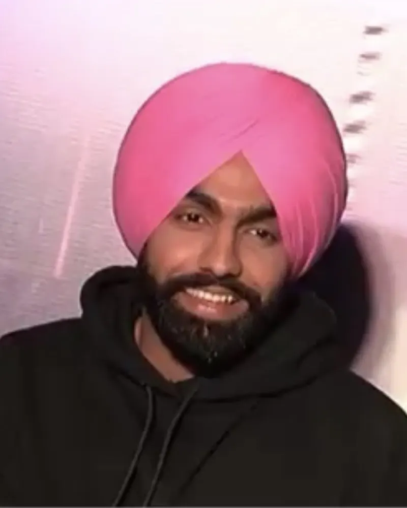 Ammy Virk smiling in a pink turban and black hoodie