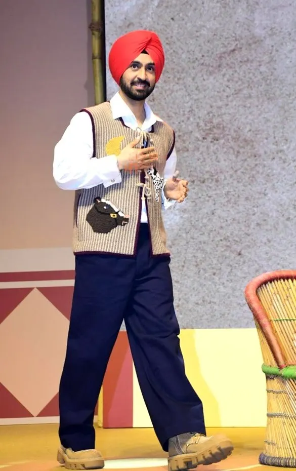 Diljit Dosanjh in a red turban walking on stage
