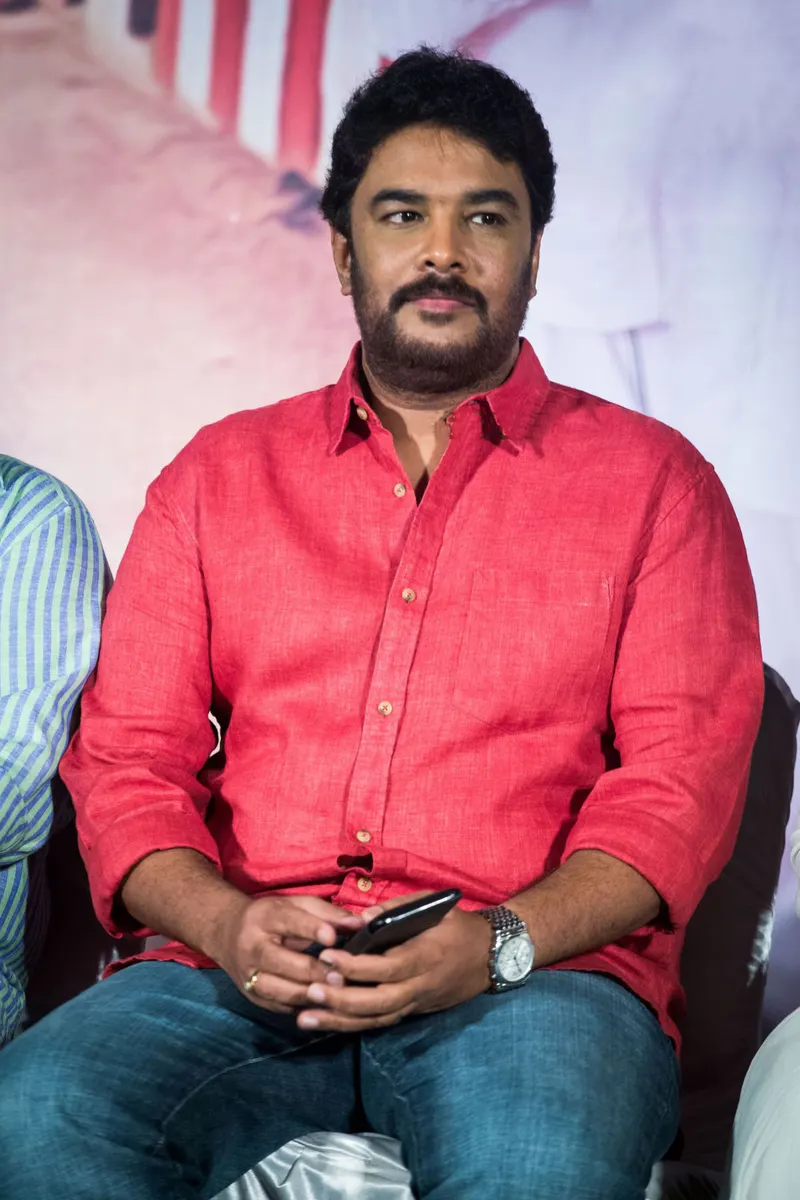 Sundar C in a red shirt seated at a launch event