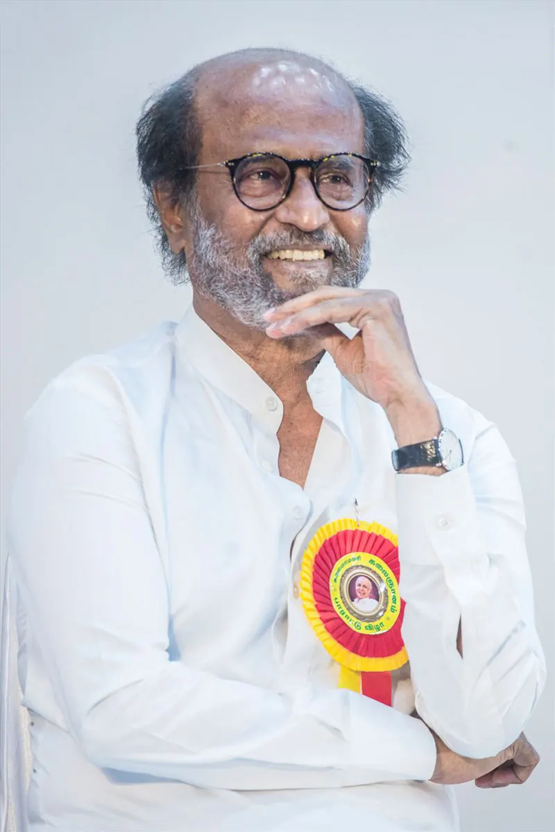 Rajinikanth in white smiling with his hand on his chin