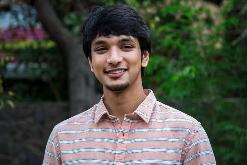 Gautham Ram Karthik smiling in a striped shirt outdoors