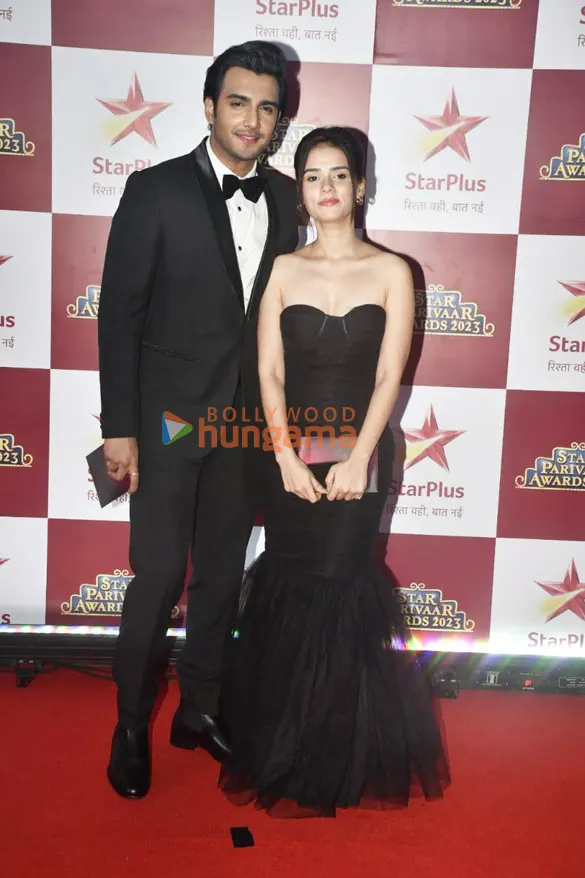 Adhik Mehta in a black tuxedo beside Nishi Saxena