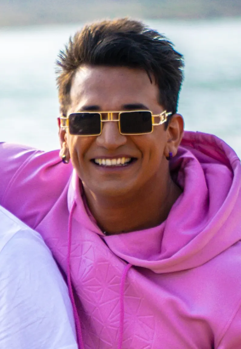 Prince Narula smiling in gold sunglasses and a pink hoodie