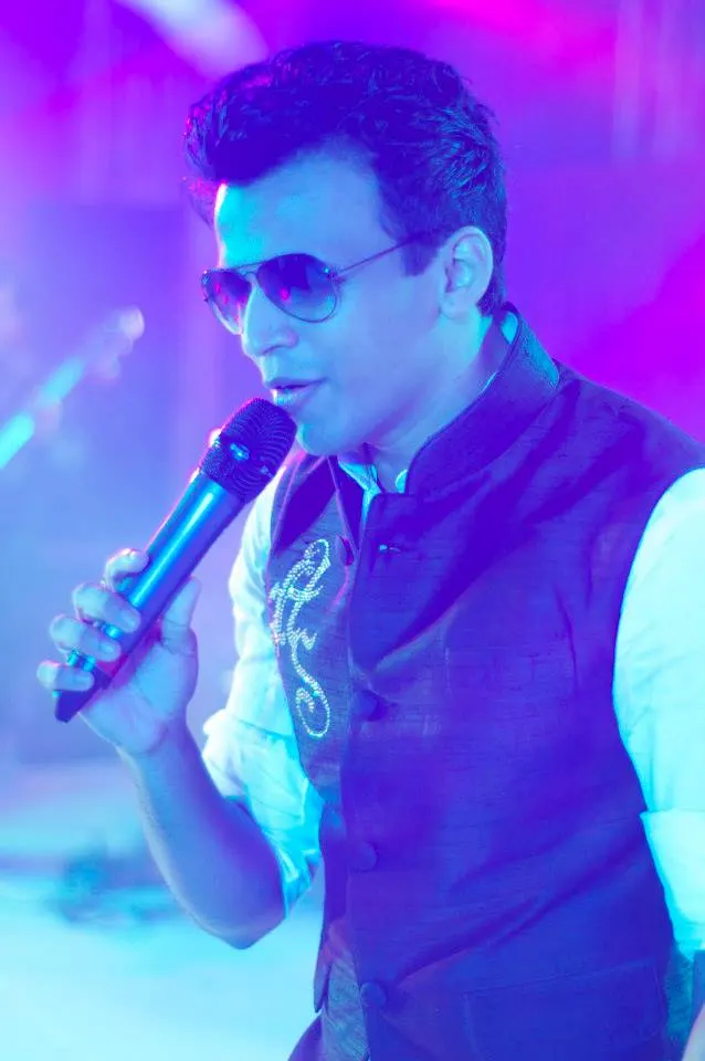 Abhijeet Sawant singing into a microphone on a lit stage