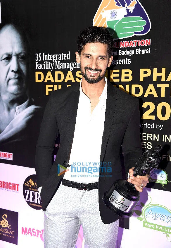 Ravie Dubey in a black blazer holding an award