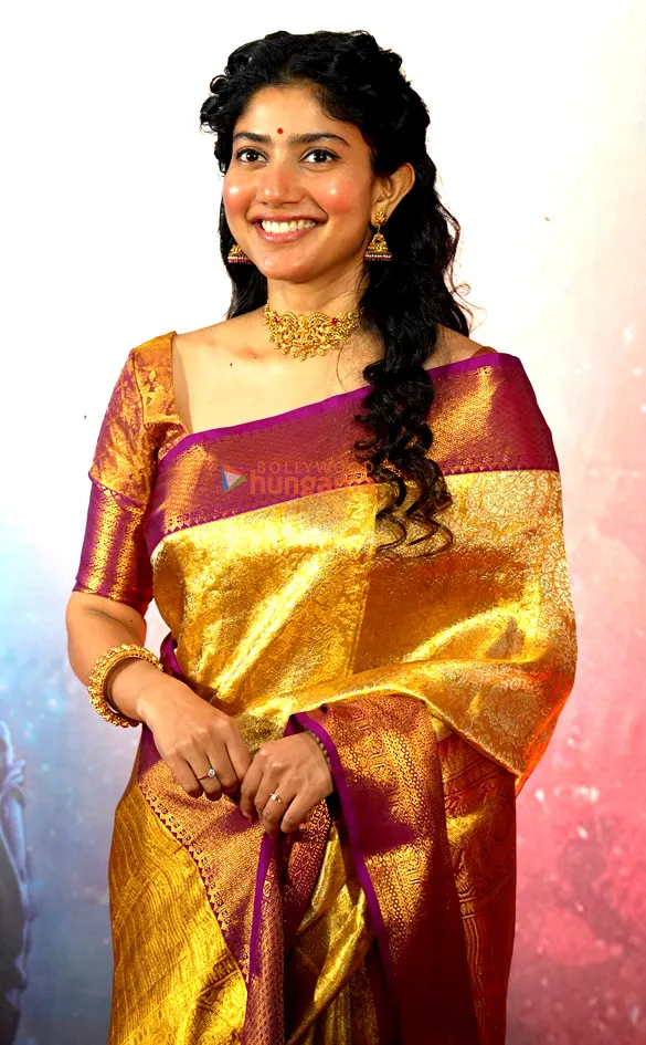 Sai Pallavi smiling in a gold and maroon silk saree