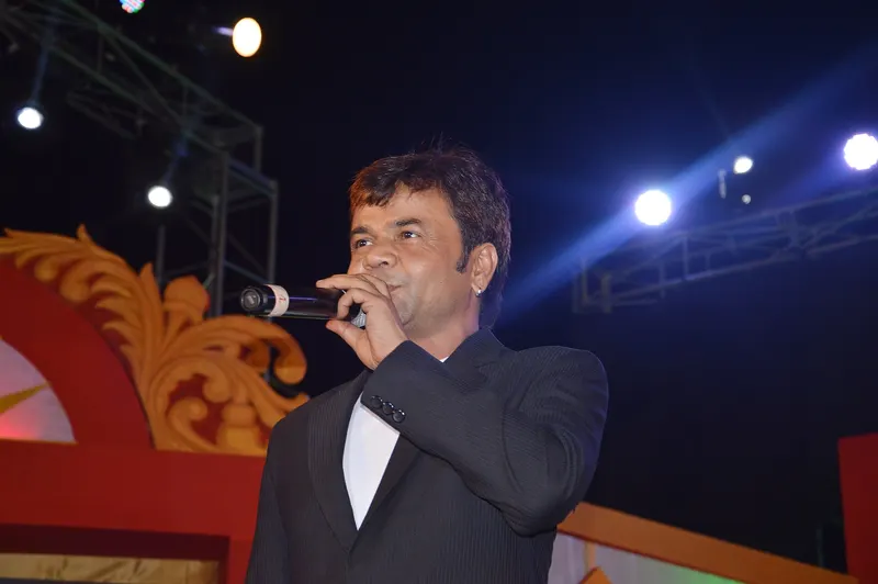 Rajpal Yadav speaking into a microphone on a stage
