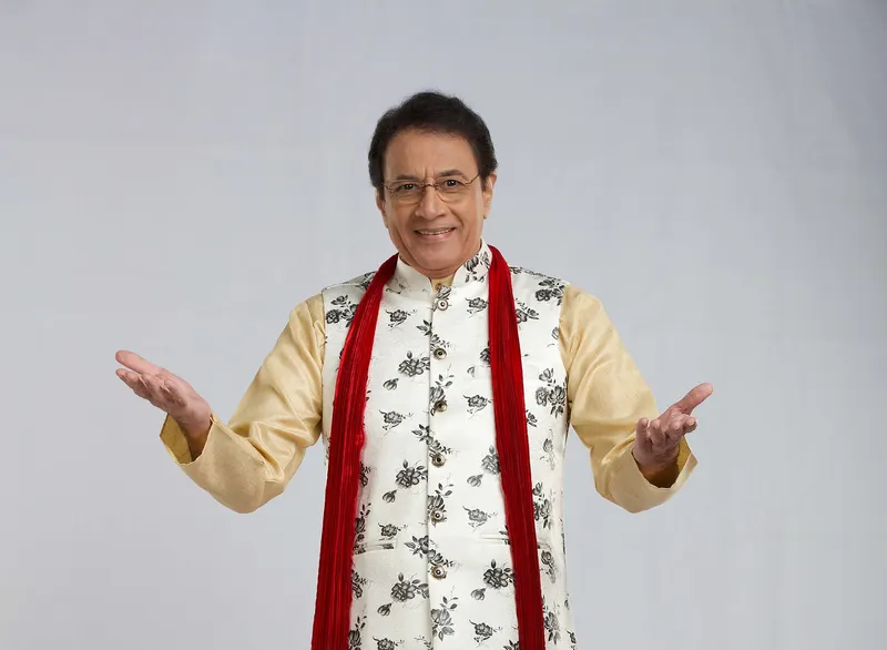 Arun Govil in a cream kurta and red scarf with arms outstretched