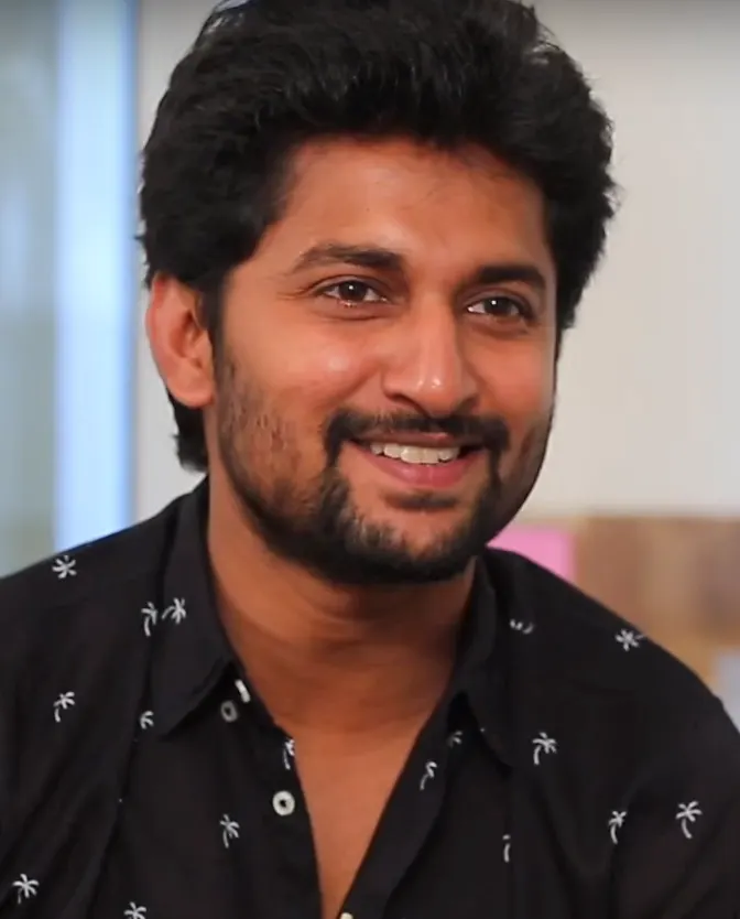 Nani smiling in a black printed shirt