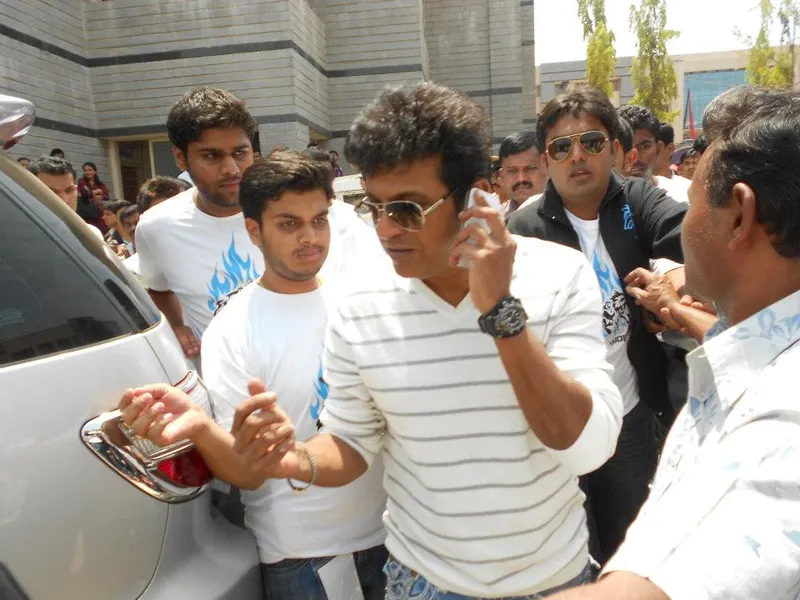 Shivarajkumar in sunglasses greeting a crowd of students