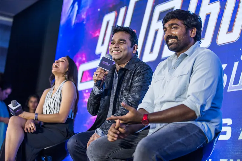 Vijay Sethupathi laughing on stage beside AR Rahman